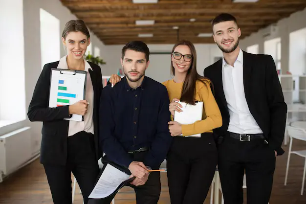 group young smiling business people classic suits joyfully looking camera together while spending time work modern office_574295 5897